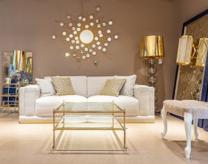 Stylish living room with white sofa, gold decor, and glass table for modern homes.